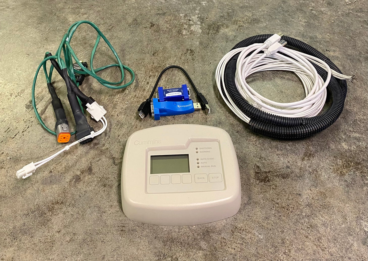 An electric heating or cooling controller kit laid out on a concrete floor, including a beige control panel, a blue electronic module, green and white wires, and a black corrugated conduit with white wires.